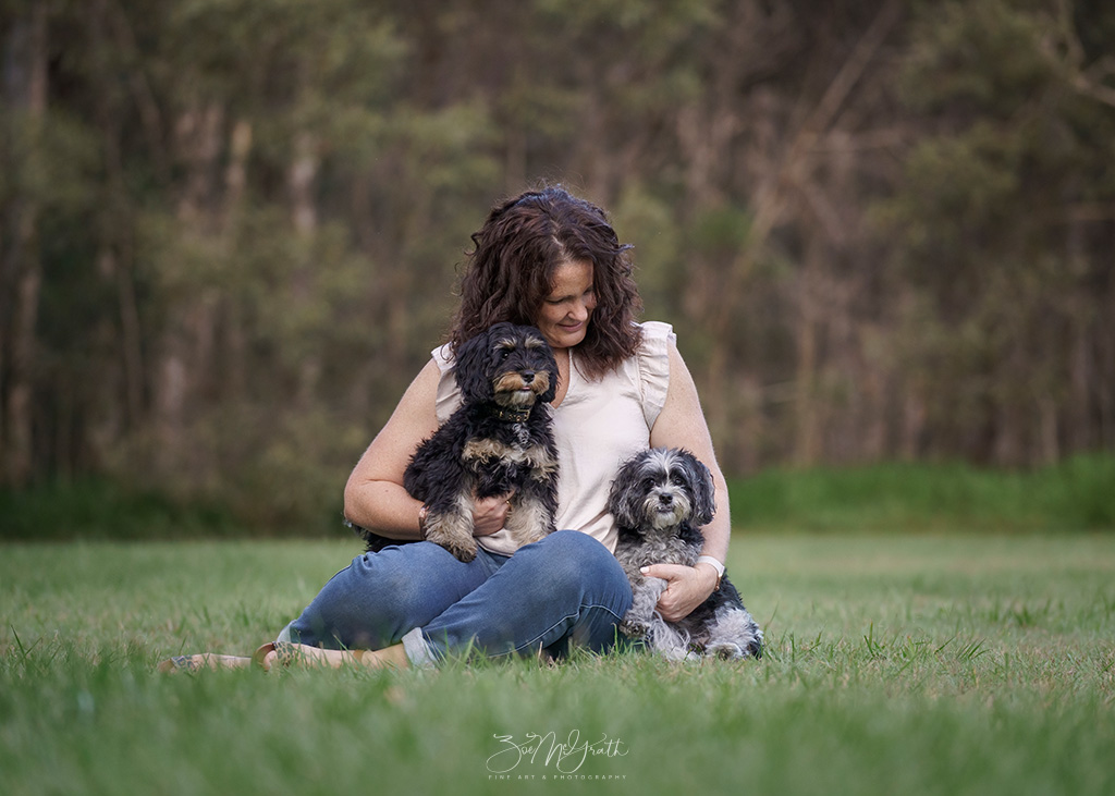 A woman holding her dog close at golden hour
